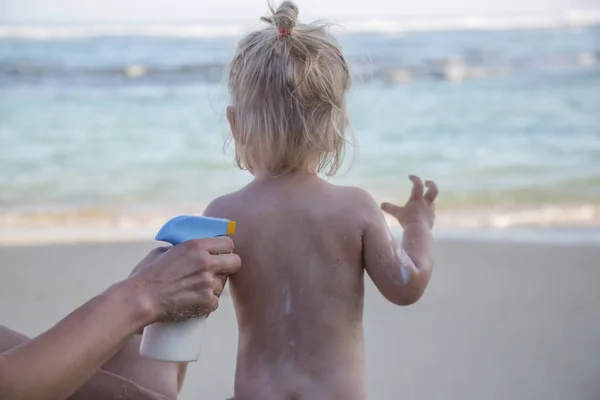 海滩上的日光浴 母亲应用防晒霜保护霜她的幼儿 — 图库照片