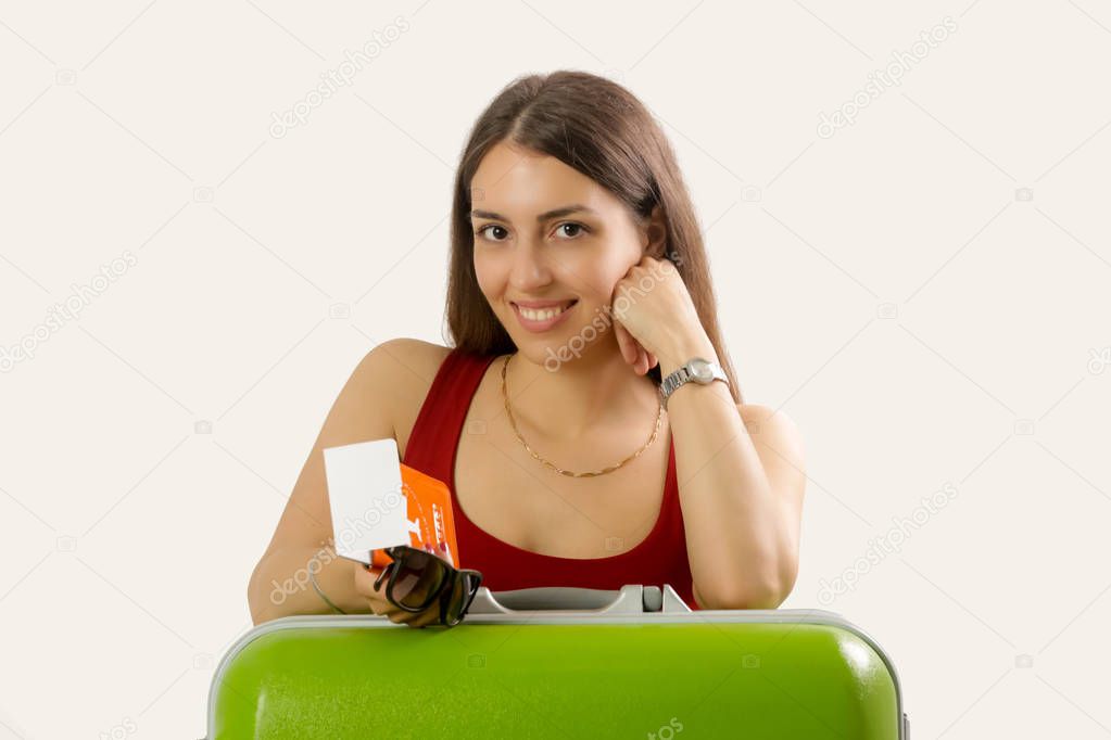 Studio portrait of a young woman leaning on the big green suitcase and holding passport and tickets, travel, summer vacation conceptCategoryPeople