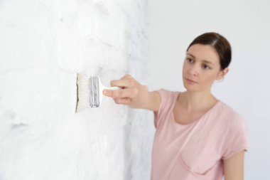 Beyaz tuğla duvara boya yla boya yla boyaren kadın