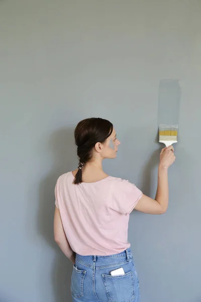 Γυναίκα Ζωγραφική Γκρι Χρώμα Πάνω Από Ένα Λευκό Τοίχο — Φωτογραφία Αρχείου