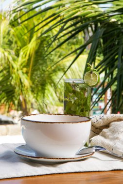 A glass of nonalcoholic mojito and a portion of a delicious organic green smoothie bowl, healthy and tasty summer meal clipart