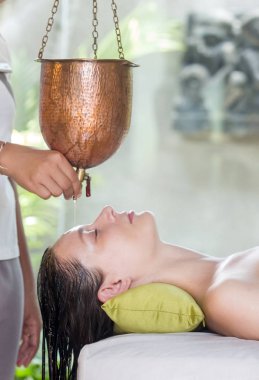 Shirodhara, Ayurveda şifa tekniği. Kadın alnına yağ damlıyor. Alnına ve saçına damlayan aromatik yağ ile ayurvedik masaj oturumunda genç bir kadının portresi.