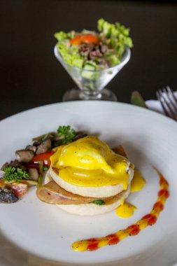 Yumurta Benedict -Amerikan kahvaltı veya brunch çanak bir İngiliz muffin iki yarısı bir haşlanmış yumurta, pastırma veya jambon ile tepesinde oluşur ve hollandaise sos. 