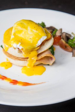 Yumurta Benedict -Amerikan kahvaltı veya brunch çanak bir İngiliz muffin iki yarısı bir haşlanmış yumurta, pastırma veya jambon ile tepesinde oluşur ve hollandaise sos. 