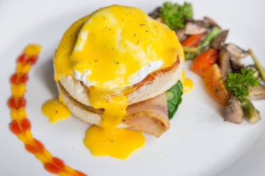 Yumurta Benedict -Amerikan kahvaltı veya brunch çanak bir İngiliz muffin iki yarısı bir haşlanmış yumurta, pastırma veya jambon ile tepesinde oluşur ve hollandaise sos. 