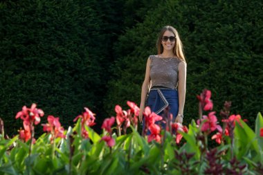 Mutlu genç kadın çiçekler, güzel esmer samimi açık hava portresi yakınında bir parkta ayakta