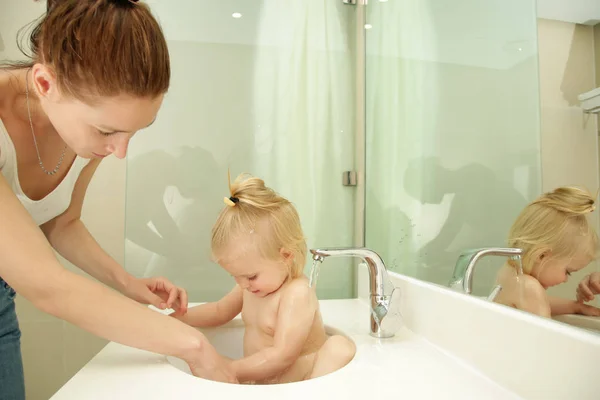 かわいいブロンドの赤ちゃんは バスルームのシンクでお風呂を取ります — ストック写真