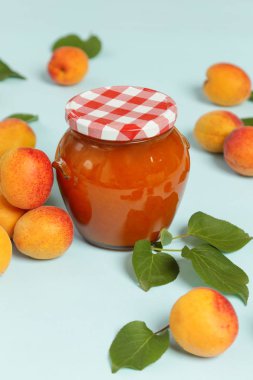 Mavi arka planda Kayısı reçeli ve taze kayısı kavanozu