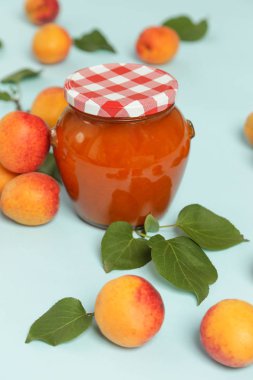 Mavi arka planda Kayısı reçeli ve taze kayısı kavanozu