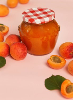 Pembe arka planda Kayısı reçeli ve taze kayısı kavanozu