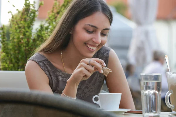 Bir kafede oturan ve bir kahve şeker ekleyerek genç bir güzel kadın Portresi
