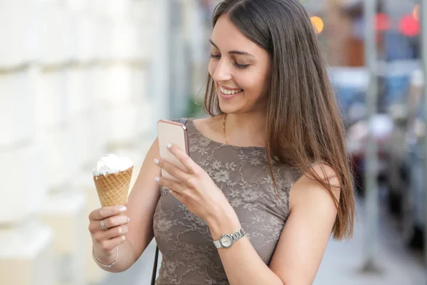 バニラアイスクリームコーンの写真を持って 街の通りで若い笑顔の女性 — ストック写真