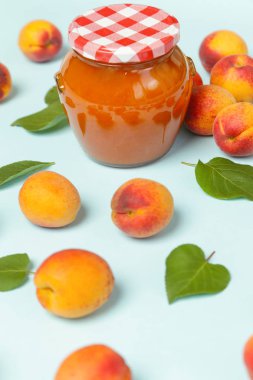 Mavi arka planda Kayısı reçeli ve taze kayısı kavanozu