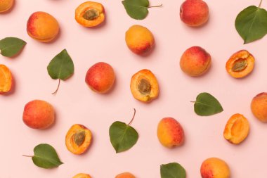 Pembe bir arka planda kayısı, düz olgun kayısı ve yaprakları görüntü yatıyordu