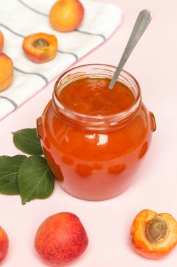 Pembe arka planda Kayısı reçeli ve taze kayısı kavanozu