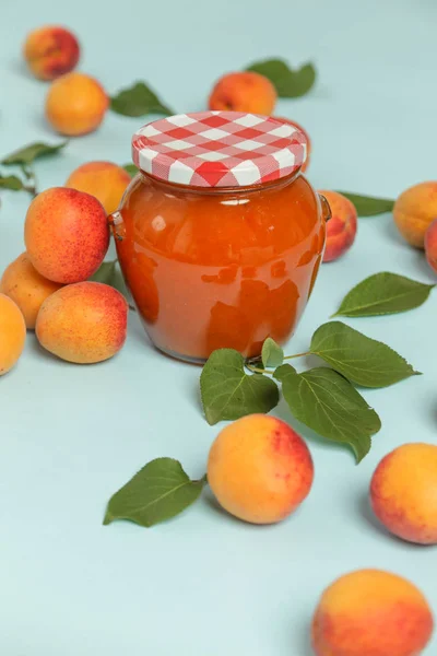 Potje Abrikozen Jam Verse Abrikozen Een Blauwe Achtergrond — Stockfoto