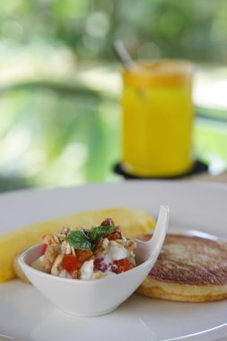 Masada servis edilen kahvaltı, müsli meyve salatası, Amerikan Pancake, omlet ve bir bardak taze portakal suyu