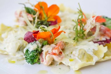 Yenilebilir çiçeklerle süslenmiş tabakta ravioli bir kısmı