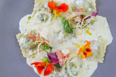 Yenilebilir çiçeklerle süslenmiş tabakta ravioli bir kısmı