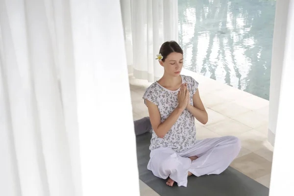 Woman with eyes closed sitting in lotus yoga position
