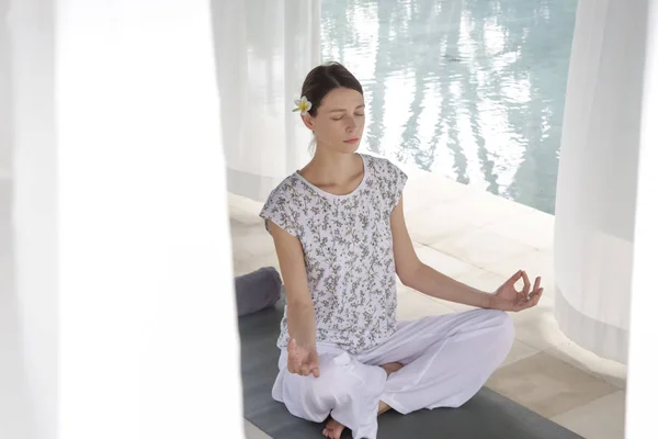 Woman meditating in a lotus yoga position at the pool, hand close up