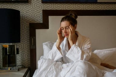 Genç üzgün kadın yatakta oturan, depresyon, anksiyete, ilişki zorlukları, migren veya sabah bulantısı kavramı