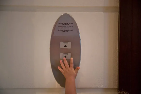 エレベーターのボタンに手を伸ばそうとする子供の手 大人のコンセプト — ストック写真