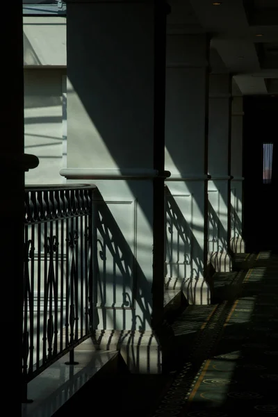 Columns and fences with strong shadows on the hallway, classic architectural detail