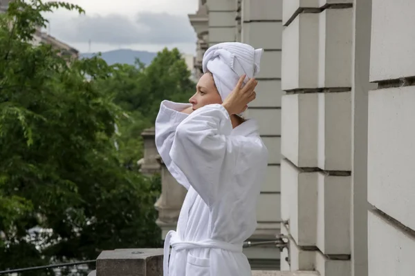 Woman in a bathrobe enjoying fresh morning air on the balcony