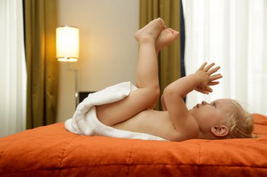 Banyo dan sonra havluya sarılmış yatakta yatan mutlu bebeğin yan görünümü