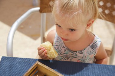 Mutlu yürümeye başlayan kız restoran masada oturan ve taze pişmiş ekmek yeme