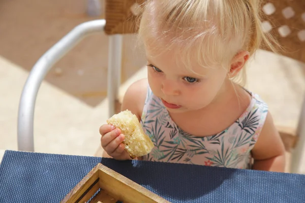 Mutlu yürümeye başlayan kız restoran masada oturan ve taze pişmiş ekmek yeme