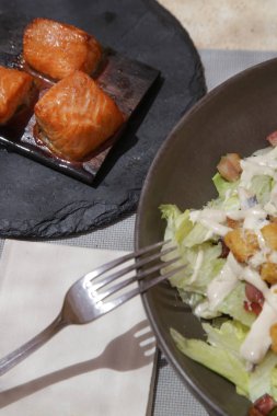 Restoran masasında servis edilen ızgara ton balığı parçaları ile Bir Sezar salatası, lezzetli ve sağlıklı yaz yemeği