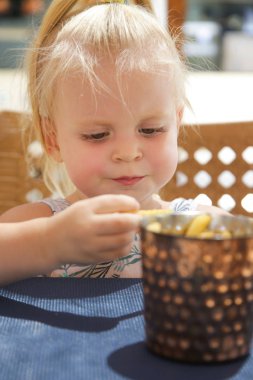 Mutlu yürümeye başlayan kız restoran masada oturan ve patates kızartması yemek