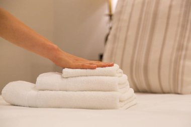Oda servisi. Otel odasında havlu değiştiren kadın. Housecleaner yatağa havlu koyarak, müşterilerin taşınması için her şeyi hazırlanıyor