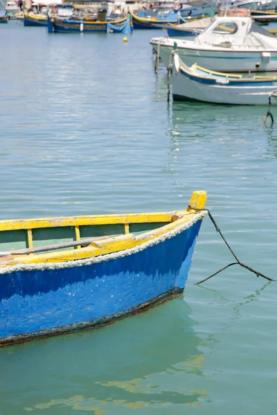 Small blue fishing boat in the clean water, water bay in Marsaxlokk, Malta\'s largest fishing village