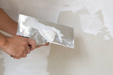 Macun bıçağı ile duvar sıva süreci. Duvar yüzeyinin sabitlenmesi ve boyama için hazırlık, ev yenileme konsepti
