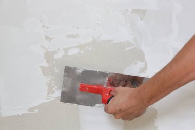 Macun bıçağı ile duvar sıva süreci. Duvar yüzeyinin sabitlenmesi ve boyama için hazırlık, ev yenileme konsepti