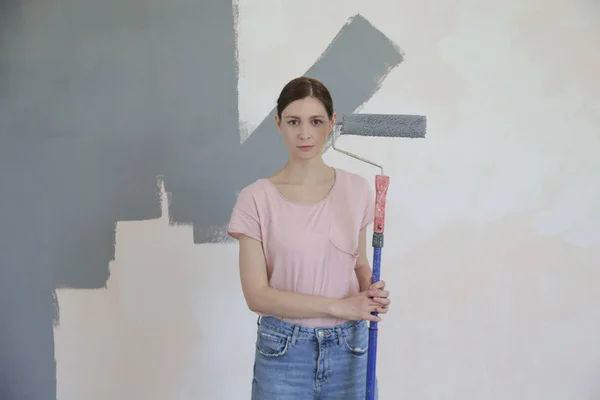 在白色墙壁上涂上灰色油漆的妇女 — 图库照片
