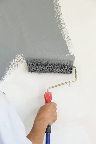 Paint roller. Painting with gray paint over a white wall