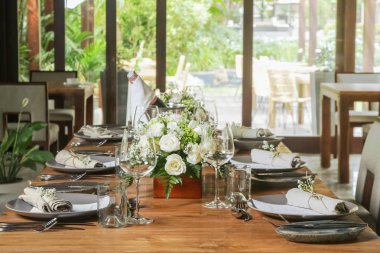 Ahşap masa, beyaz güller ve seramik tabaklar üzerinde güzel düzenleme. Boho şık düğün masası ayarı. 