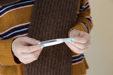 Termometre de onun sıcaklığını kontrol bir yün eşarp sarılmış genç ateşli kadın Stüdyo çekim.