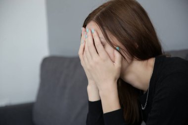 Depresif kadın portresi kanepede oturan, elleriyle yüz kapsayan