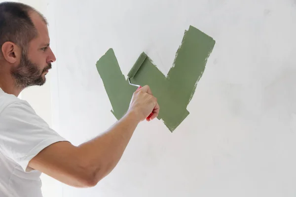 Человек Рисует Зеленой Краской Над Белой Стеной — стоковое фото