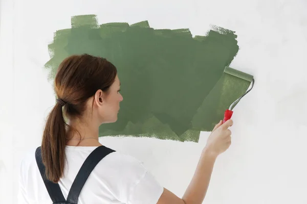 Женщина Рисует Зелёной Краской Над Белой Стеной — стоковое фото