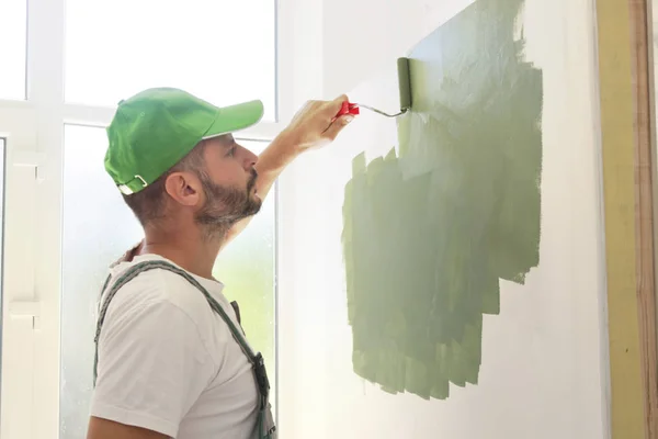 Человек Рисует Зеленой Краской Над Белой Стеной — стоковое фото