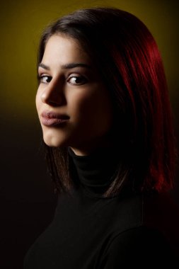 Siyah gömlekli güzel bir esmerin stüdyo portresi. Tarafsız bir yüz ifadesi.