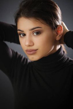 Siyah gömlekli güzel bir esmerin stüdyo portresi. Tarafsız bir yüz ifadesi.