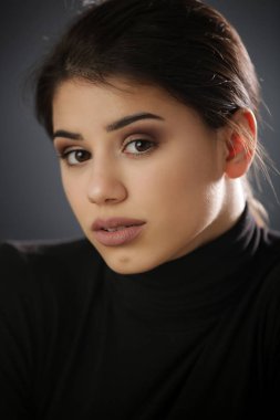 Siyah gömlekli güzel bir esmerin stüdyo portresi. Tarafsız bir yüz ifadesi.