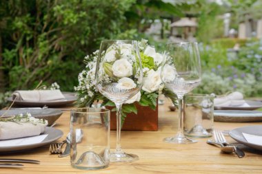 Ahşap masa, beyaz güller ve seramik tabaklar üzerinde güzel düzenleme. Boho şık düğün masası ayarı.